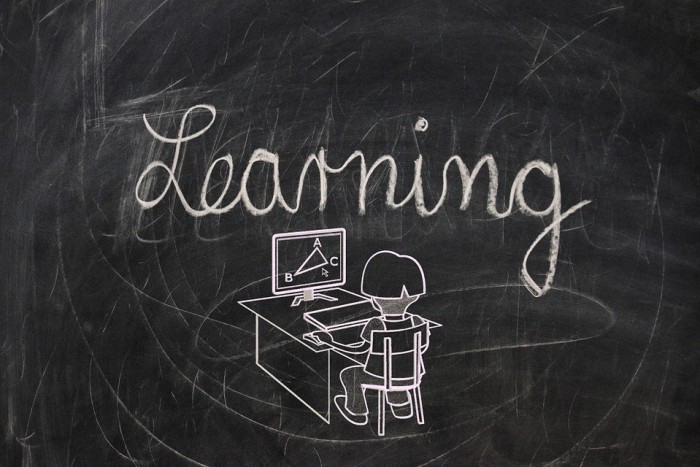 Learning drawn on a chalk board with a cartoon person working at a desk 