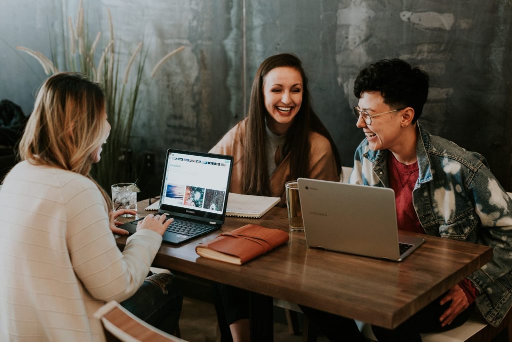3 people working at laptops and laughing 